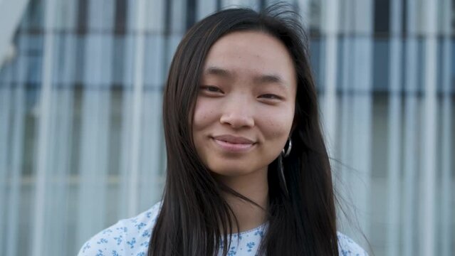 Young Asian woman looking to the camera and smile while it moving in towards to her.