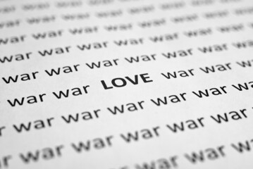 Close-up of word Love and many words War on white sheet of paper. Selective focus, macro photo