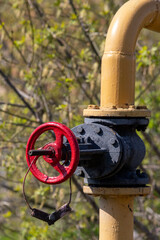 red valve on a yellow gas pipe on the street