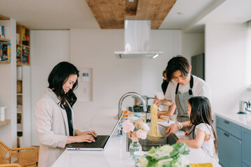 Obraz na płótnie Canvas 在宅勤務をする母と食事の準備をする父親と娘