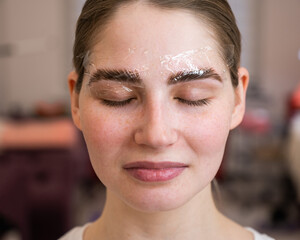 Caucasian woman on the procedure of permanent styling and coloring of eyebrows.
