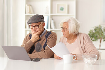 Elderly man thinking and elderly woman holding a document and looking at a computer