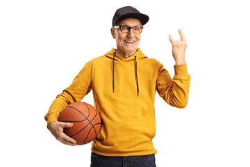 Cheerful elderly man holding a basketball and gesturing rock and roll sign