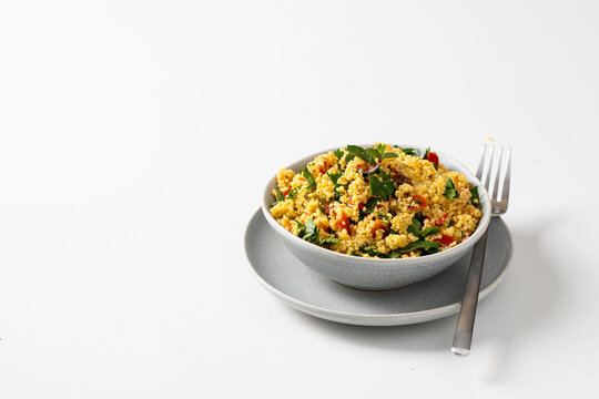Vegetarian salad  Tabule with  bulgur grain and vegetables seasoned with olive oil and lemon juice  served on white background.Copy space