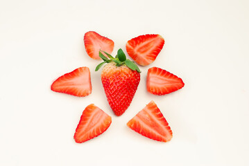 strawberry surrounded by split strawberries on white background