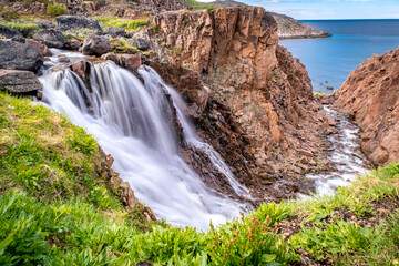Obraz premium Summer polar landscape with waterfall in Teriberka. Kola Peninsula of the Barents Sea. The nature of the north of Russia