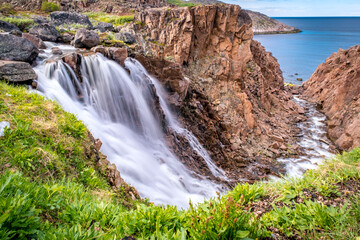 Summer polar landscape with waterfall in Teriberka. Kola Peninsula of the Barents Sea. The nature of the north of Russia