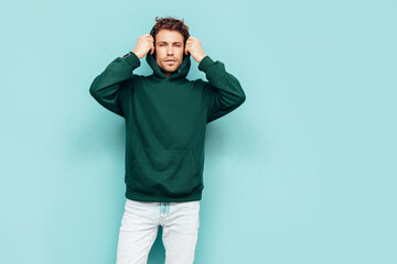 Handsome confident hipster  model.Sexy unshaven man dressed in summer stylish green hoodie and...