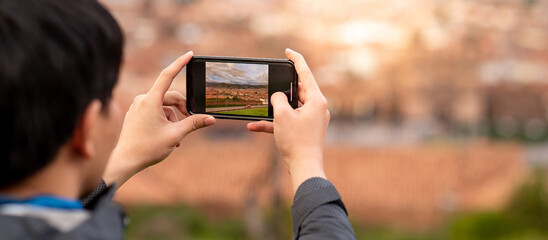 Asian man tourist taking a photo of cusco city on smartphone camera. Cusco (Cuzco) is a city in...