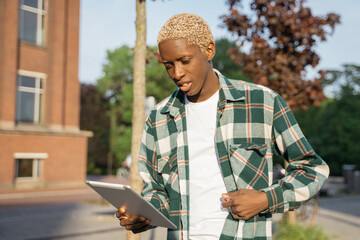 Young handsome African man wearing stylish casual clothing using digital tablet communication...