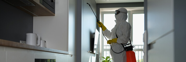 A man in a protective suit sprays an apartment