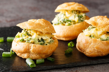 profiterole sandwiches stuffed with egg salad close-up on a slate board on the table. horizontal