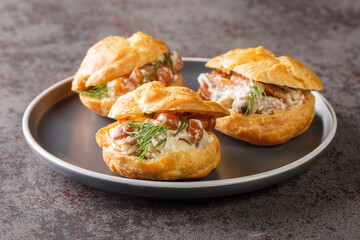 Appetizer for the holiday Profiteroles with forest mushrooms and cheese sauce close-up in a plate on the table