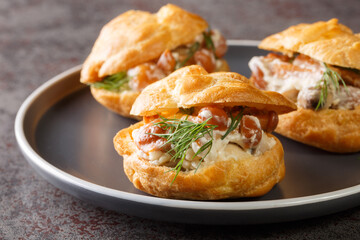 Profiteroles with forest mushrooms close-up in a plate on the table. Festive snack