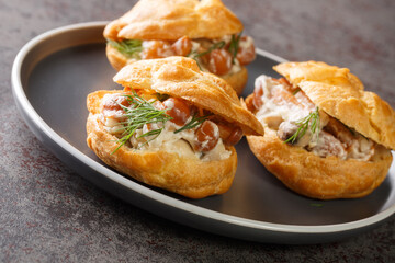 Profiteroles stuffed with stewed mushrooms with creamy sauce and dill close-up in a plate on the table
