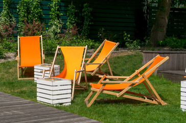 Orange lounge chairs in a green summer garden