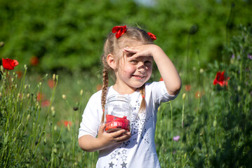 Little girl is playing in red flowers on a sunny day