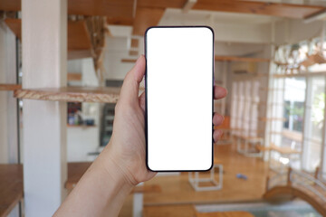 Mockup picture of business woman’s hands holding smart phone with white blank screen in modern place.