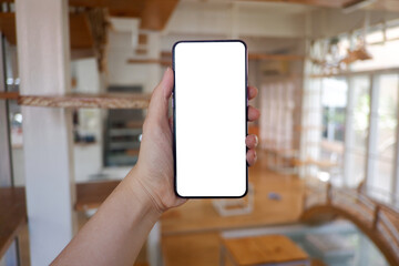 Mockup picture of business woman’s hands holding smart phone with white blank screen in modern place.
