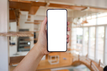 Mockup picture of business woman’s hands holding smart phone with white blank screen in modern place.