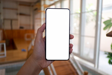 Mockup picture of business woman’s hands holding smart phone with white blank screen in modern place.