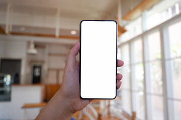 Mockup picture of business woman’s hands holding smart phone with white blank screen in modern place.