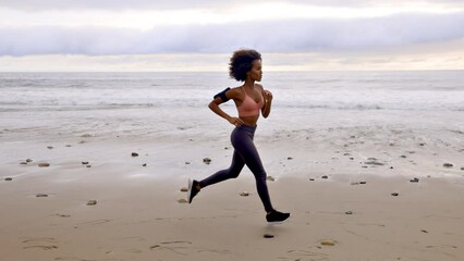 Athletic Somali woman jogging on the beach in Malibu California. Slow motion.