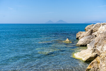 Fototapeta na wymiar blaues meer, kristallklar, im sommer in europa, baden am meer auf sizilien, mit felsen an der seite