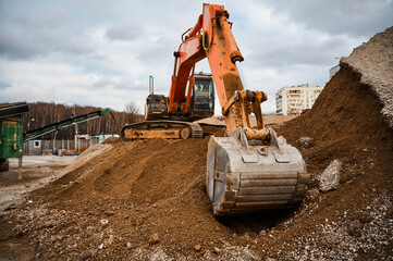 Excavator digs soil with bucket at construction site