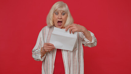 Senior woman grandmother open envelope take out letter reads it feel happy. Career growth advance promotion bank loan approve, monetary award, long-awaited invitation great news. Red studio background