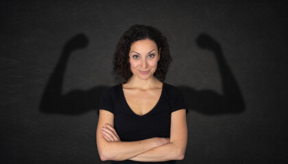 Young beautiful woman with strong arms shadow on a chalkboard background	