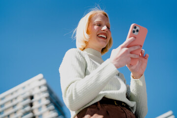 Young woman reading a message on the phone in the city.