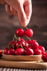 hand holding Ripe cherries on wooden background