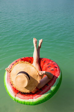 beautiful woman floating on inflatable ring in blue lake water