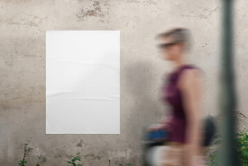Blank poster mockup on the wall for design presentation. A young woman walks past - obrazy, fototapety, plakaty