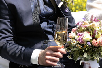 brätigam mit brautstrauss und champagnerglas im cabriolet