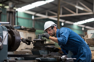Fototapeta na wymiar Engineer male worker in white hard hat working with production machinery in the factory. Factory worker maintaining CNC machine lathe metal at the industry factory.