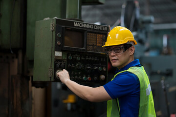 Asian engineer male worker in white hard hat working with production machinery in the factory. Asian factory worker maintaining machine at the industry factory.