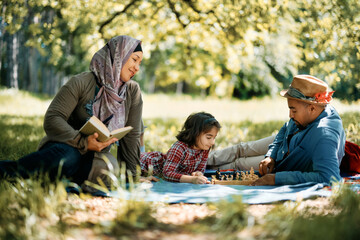 Happy Muslim family enjoys on picnic in spring day in nature.