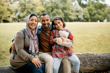 Portrait of happy Muslim family in nature and looking at camera.
