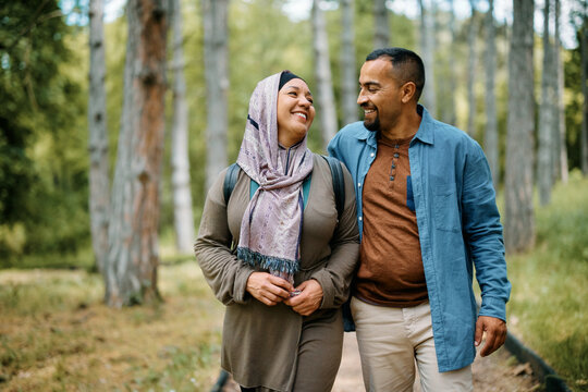 Happy Muslim couple talking while enjoying in walk in nature.