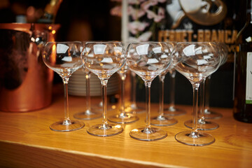 empty wine glasses stand on a wooden bar counter in a restaurant