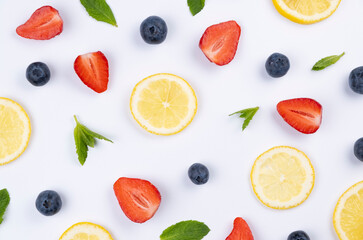  background of blueberries, strawberries, lemon slices and mint leaves on a white background - the concept of a healthy diet. Summer bright background, food design
