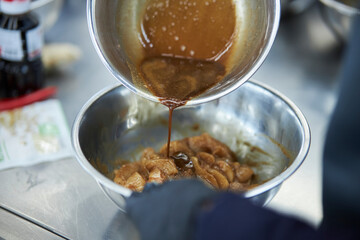 the process of cooking chicken in teriyaki sauce. cooking chicken in sweet and sour sauce. chicken pieces with teriyaki sauce in a metal bowl