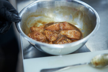 the process of cooking chicken in teriyaki sauce. cooking chicken in sweet and sour sauce. chicken pieces with teriyaki sauce in a metal bowl