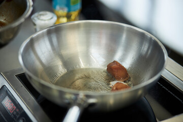 the process of cooking chicken in teriyaki sauce. cooking chicken in sweet and sour sauce. chicken pieces with teriyaki sauce in a metal bowl