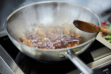 the process of cooking chicken in teriyaki sauce. cooking chicken in sweet and sour sauce. chicken pieces with teriyaki sauce in a metal bowl