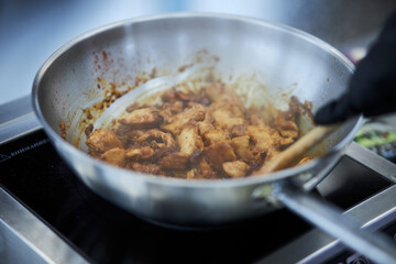 the process of cooking chicken in teriyaki sauce. cooking chicken in sweet and sour sauce. chicken pieces with teriyaki sauce in a metal bowl
