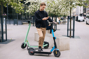 Transportation ecology. Green sustainable mobility Young man unlocks an e-scooter with his mobile...