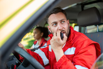 handsome young male paramedic talking by portable radio while sitting in ambulance © Graphicroyalty